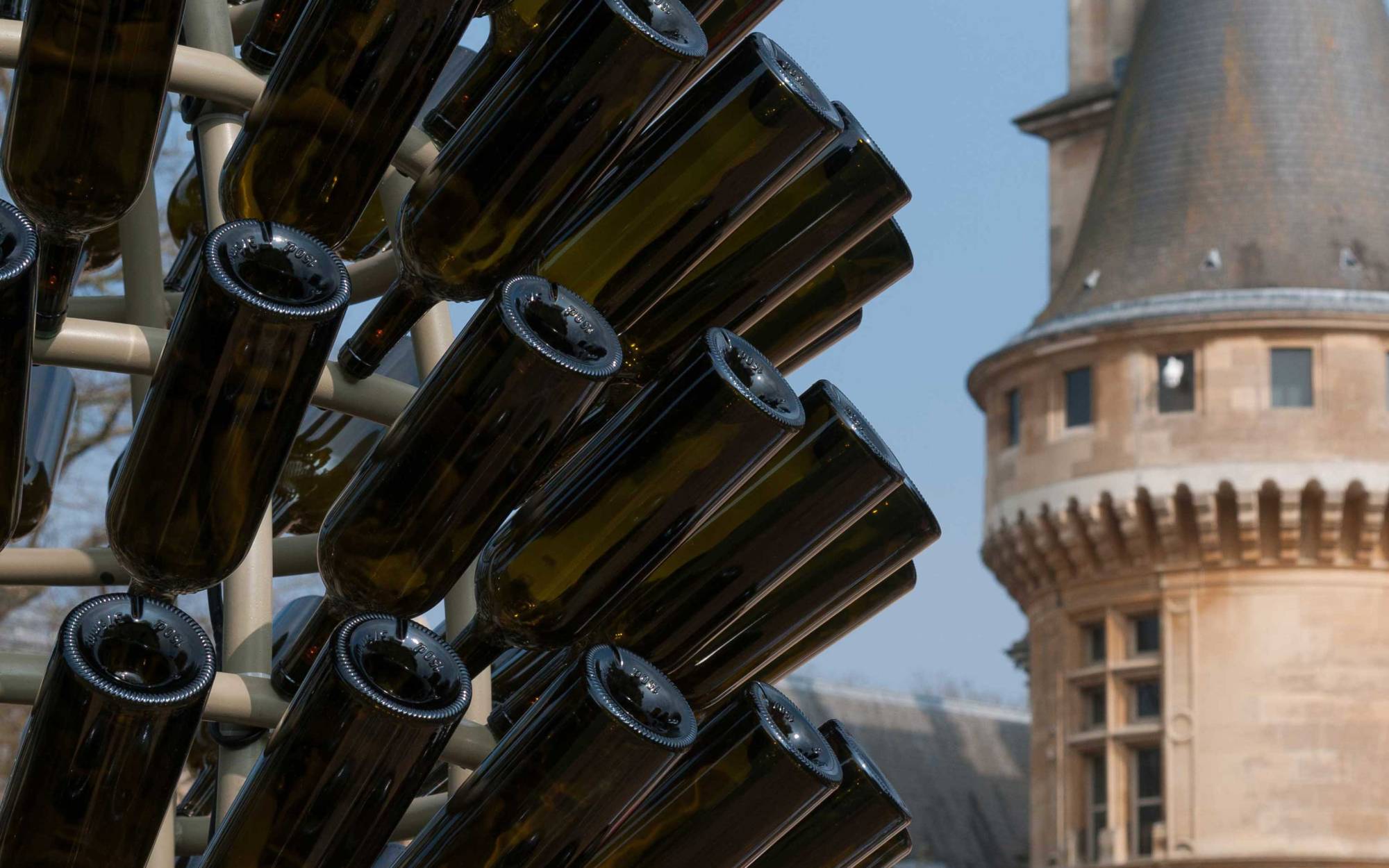 Two large outdoor sculptures shaped like candlesticks consisting of a metallized and themo-lacquered iron structure adorned with Château Lafite Rothschild wine bottles lit from inside with ultra-light LEDs.