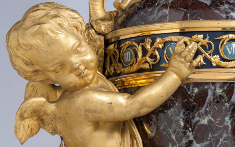 Clock set in a green marble vase supported by cupid on a marble base