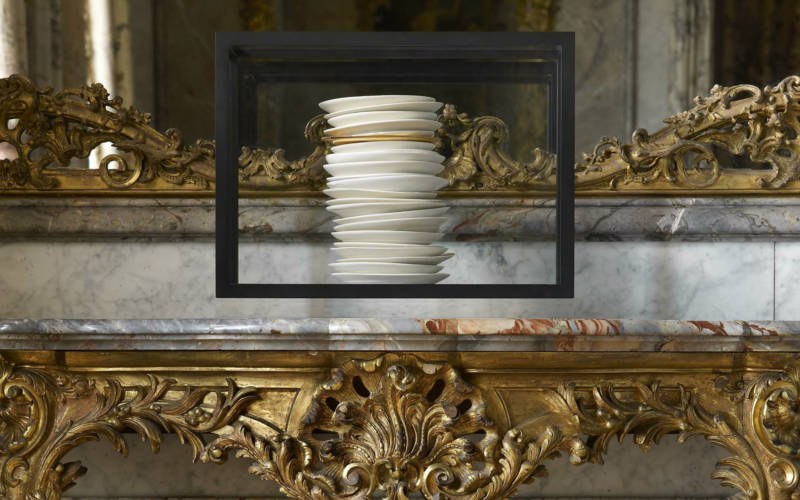 a stack of white porcelain plates by Edmund du Waal on an 18th century French side table